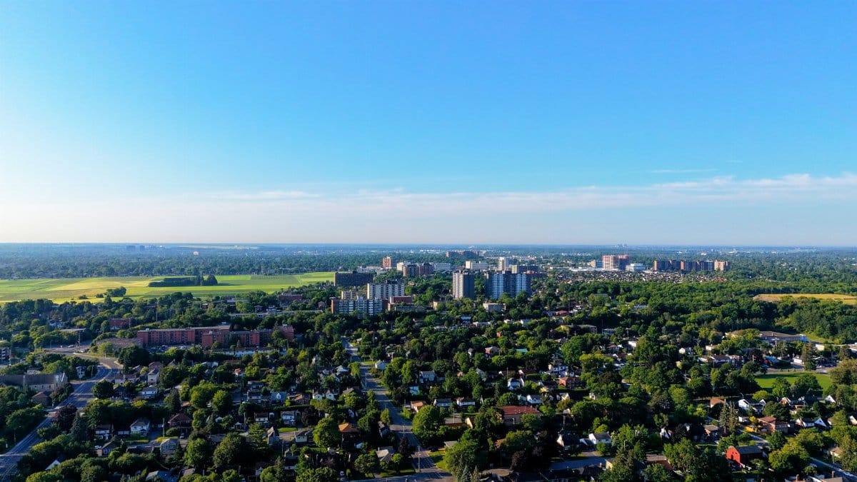 Aerial view of cityscape with residential and green areas under a clear blue sky.