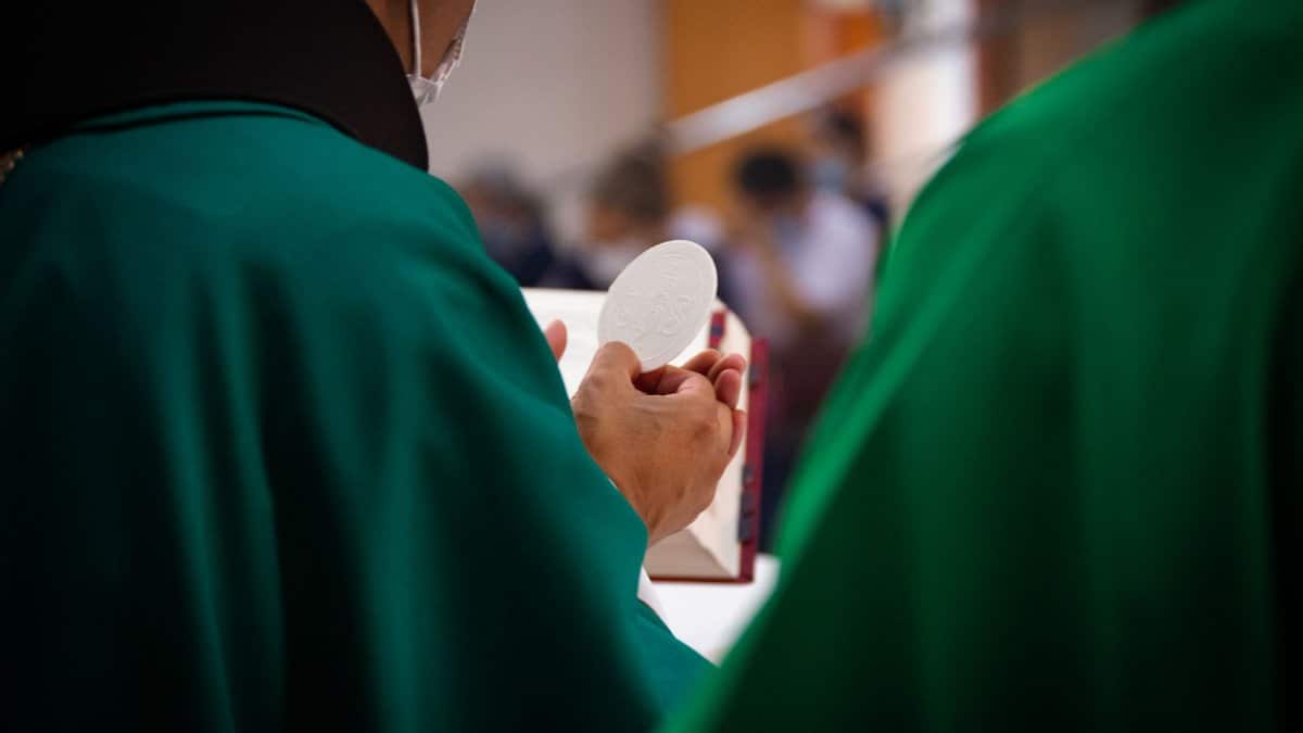 A close-up of a priest holding a communion wafer during a Catholic mass in Ecuador.