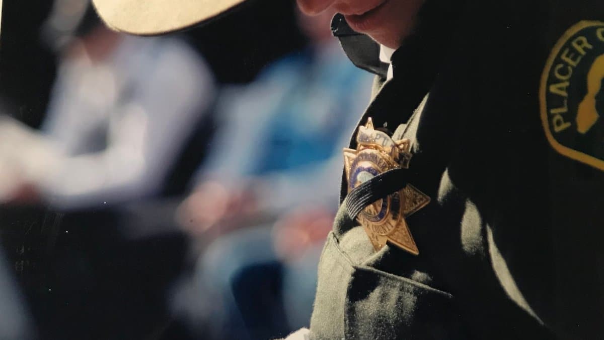 A focused shot of a police officer wearing a uniform and badge outdoors with shallow depth of field.