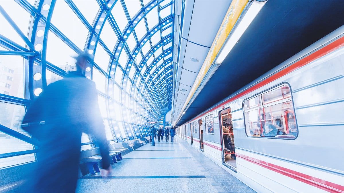 Blurred commuters rushing in a modern subway station with striking architecture and light play.