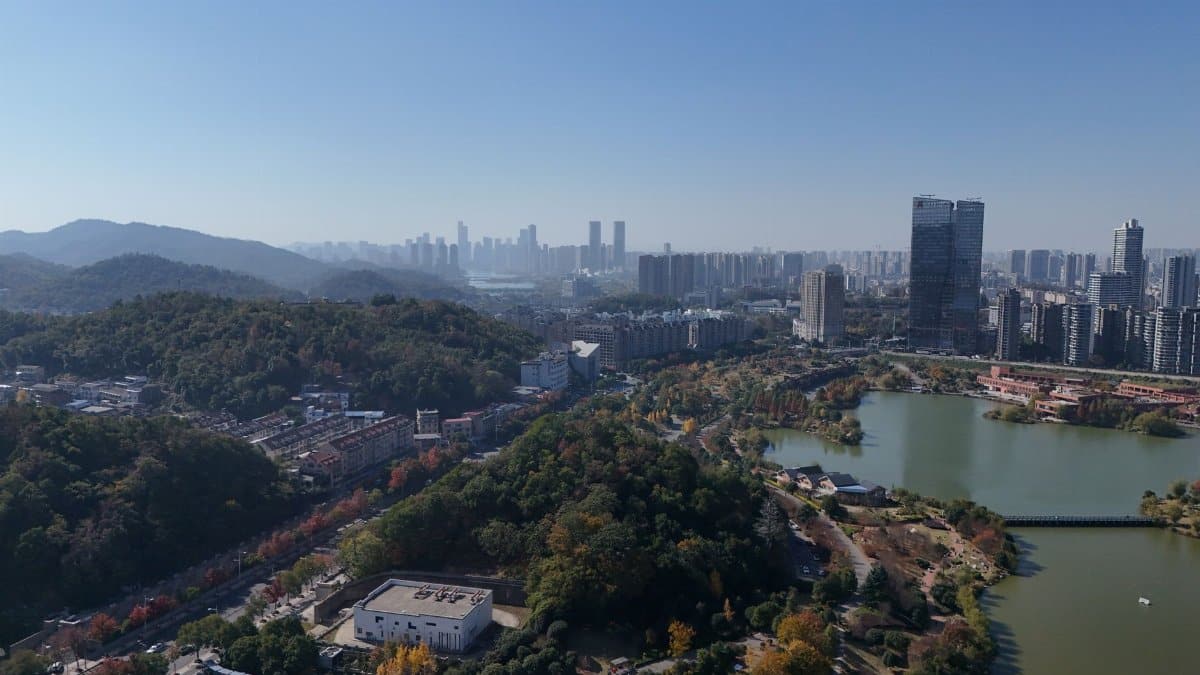 Aerial cityscape of Changsha, China, showcasing vibrant hills and a sprawling urban skyline under a clear blue sky.