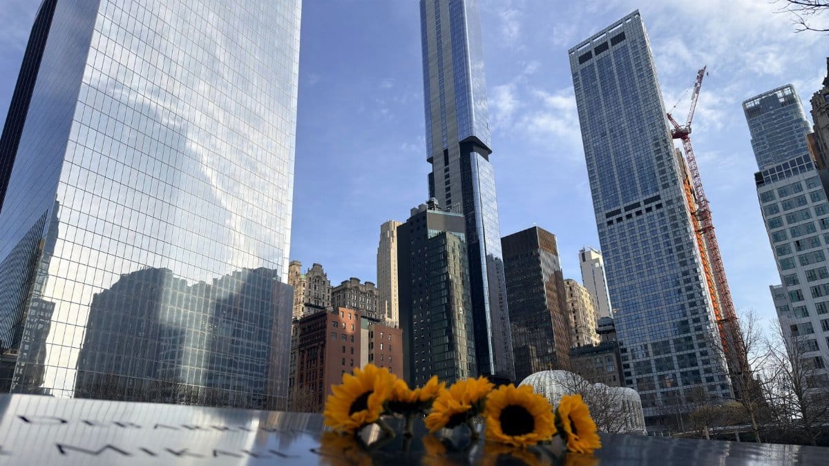 Sunflowers adorn a memorial in front of New York City's iconic skyline, showcasing poignant remembrance.