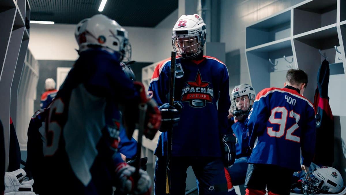 Young hockey players in the locker room gearing up for a match, showcasing teamwork and preparation.