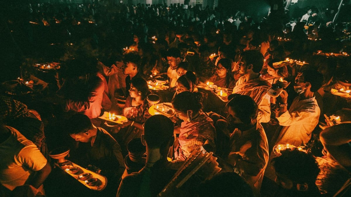 A festive crowd illuminated by candlelight during a vibrant celebration at night, creating a warm and communal atmosphere.