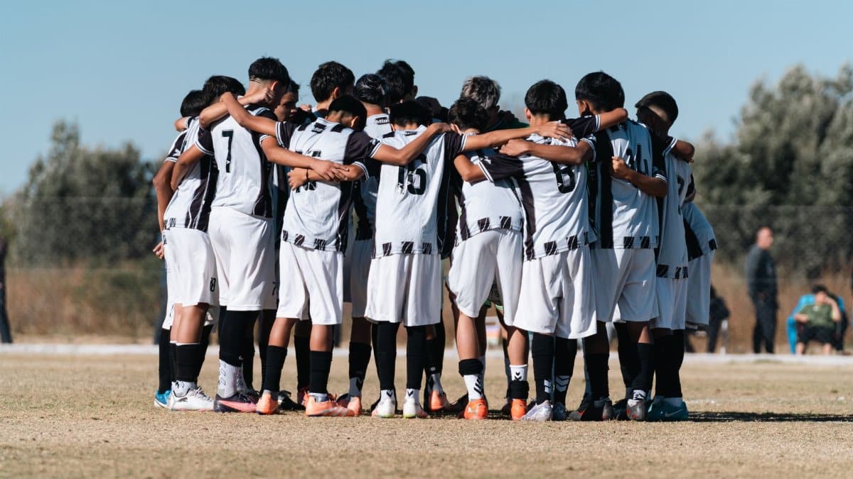 Youth soccer team huddling on the field, preparing for the game together.