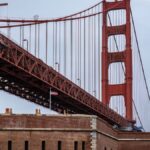 Close-up of the iconic Golden Gate Bridge with cloudy sky in San Francisco, showcasing architectural detail.