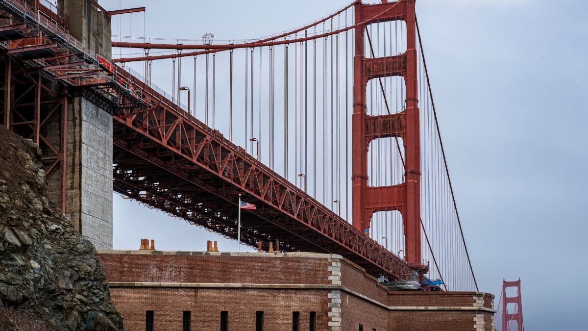 Close-up of the iconic Golden Gate Bridge with cloudy sky in San Francisco, showcasing architectural detail.