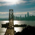 A stunning view of the Golden Gate Bridge and San Francisco skyline at sunset with vibrant colors and reflections.