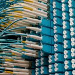 Detailed view of fiber optic patch cables connecting to a blue patch panel in a data center.