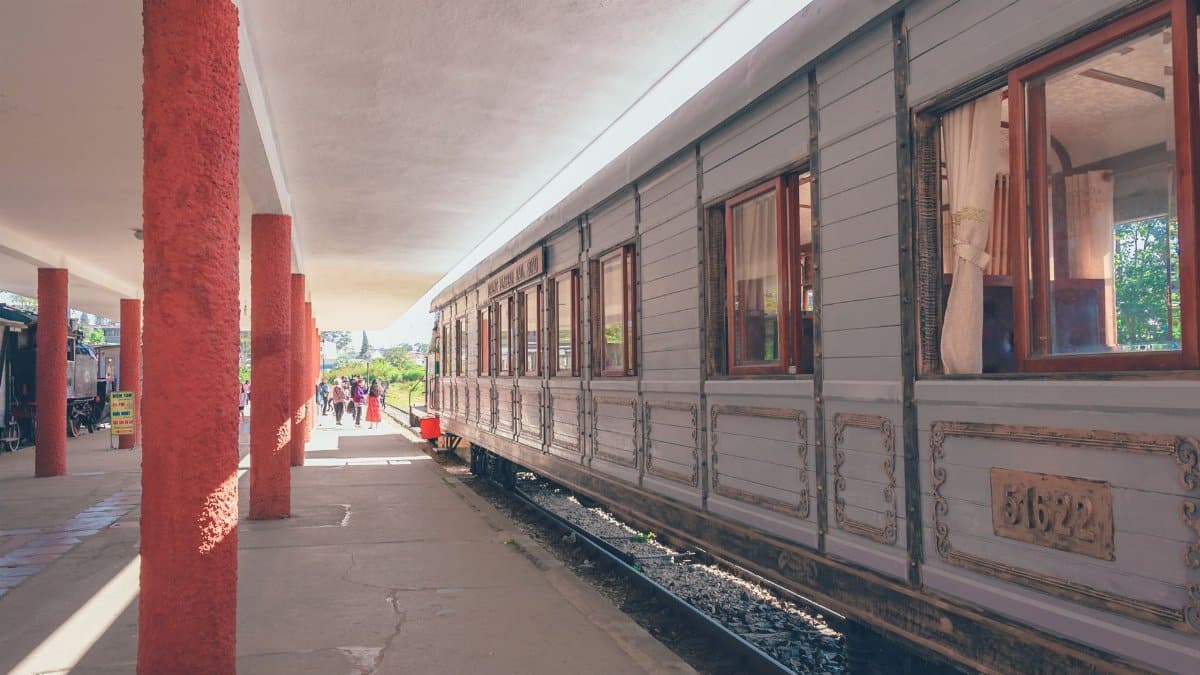 Vintage train at a sunlit platform with commuters walking by. Urban transportation scene.