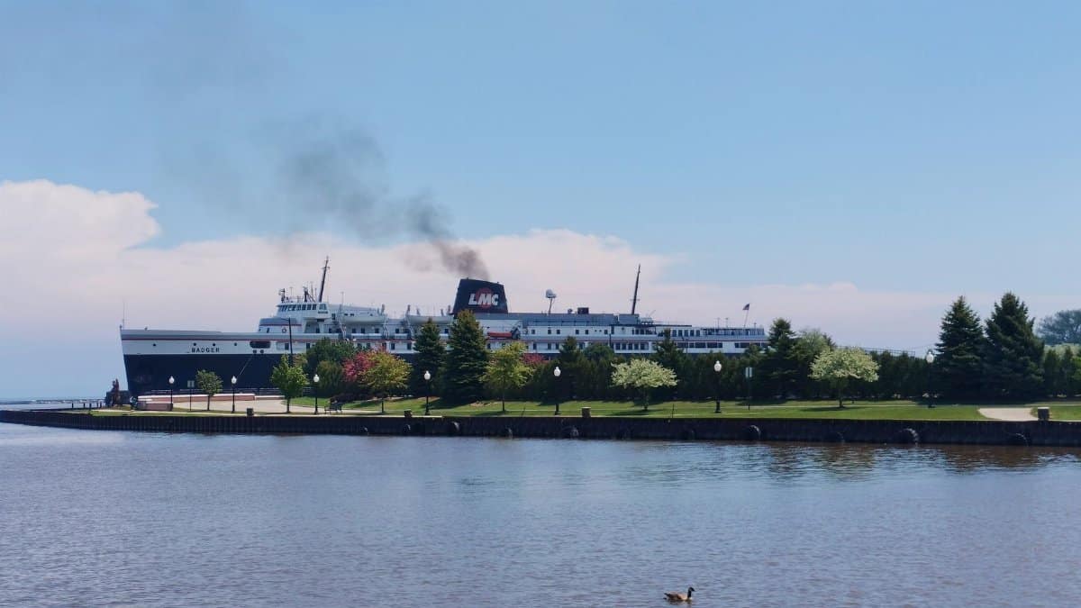 View of SS Badger ferry docked at Manitowoc harbor on a clear summer day.