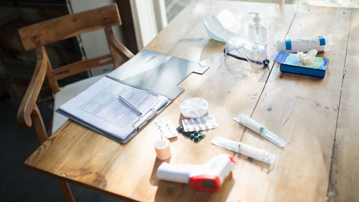 A spread of medical supplies and COVID-19 essentials on a sunlit wooden table.