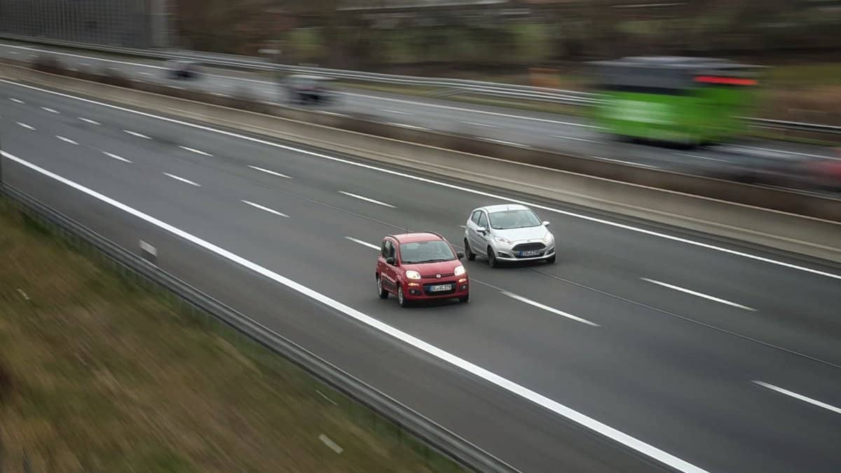Two cars moving fast on a highway, showcasing speed and travel in motion.