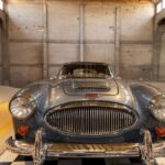 Front view of a vintage Austin-Healey car displayed in a classic industrial warehouse setting.