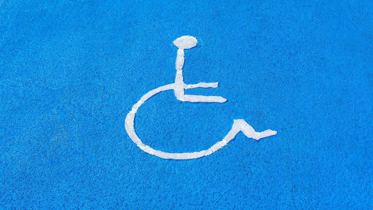 Clear blue disabled parking sign on asphalt surface, symbolizing accessibility.