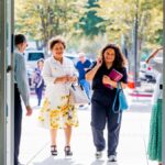 A group of people walking into a building, smiling, on a sunny day.