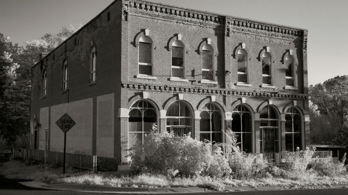 Black and white photo of a historic building in Weaver, MN with a dead-end sign.