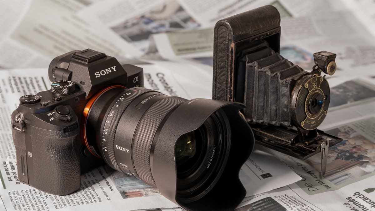Side-by-side comparison of a modern and vintage camera on newspapers.