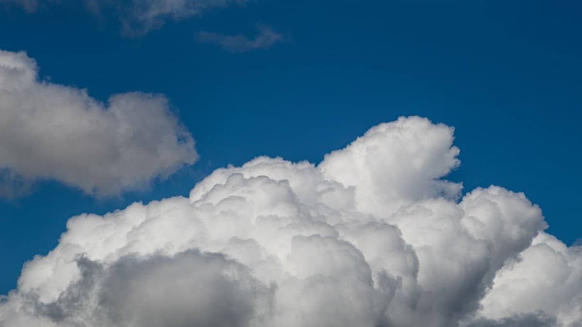 Vibrant cumulus clouds fill a bright blue sky, showcasing nature's beauty.
