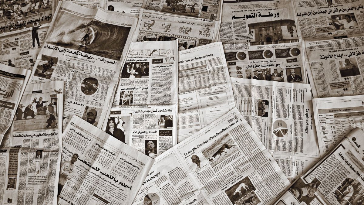 A variety of Arabic and French newspapers spread out, showcasing diverse articles and images.