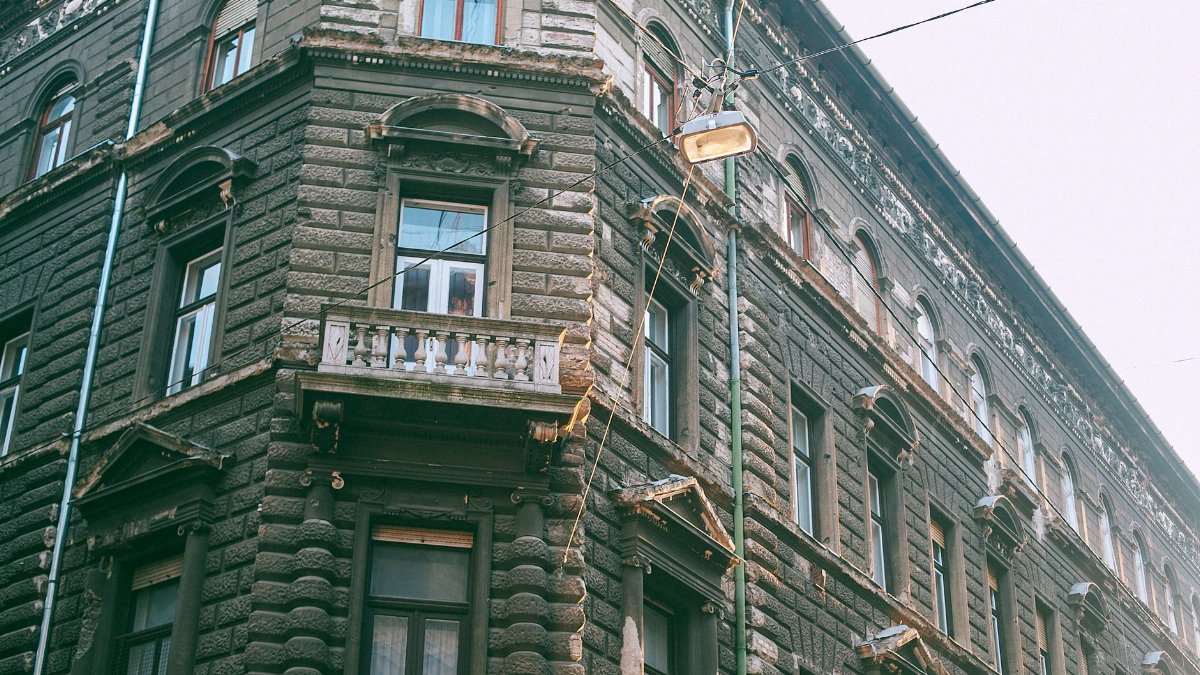From below of exterior of classic dwell apartment house with ornamental windows and small balcony in town