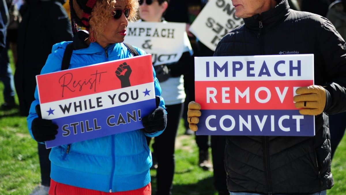 Protesters gather in Baltimore holding signs advocating for political change.