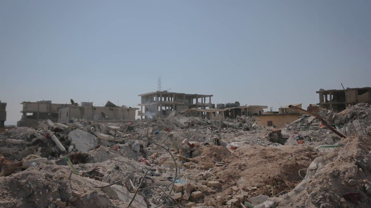 Urban ruins and debris in Idlib after a natural disaster under a clear sky.