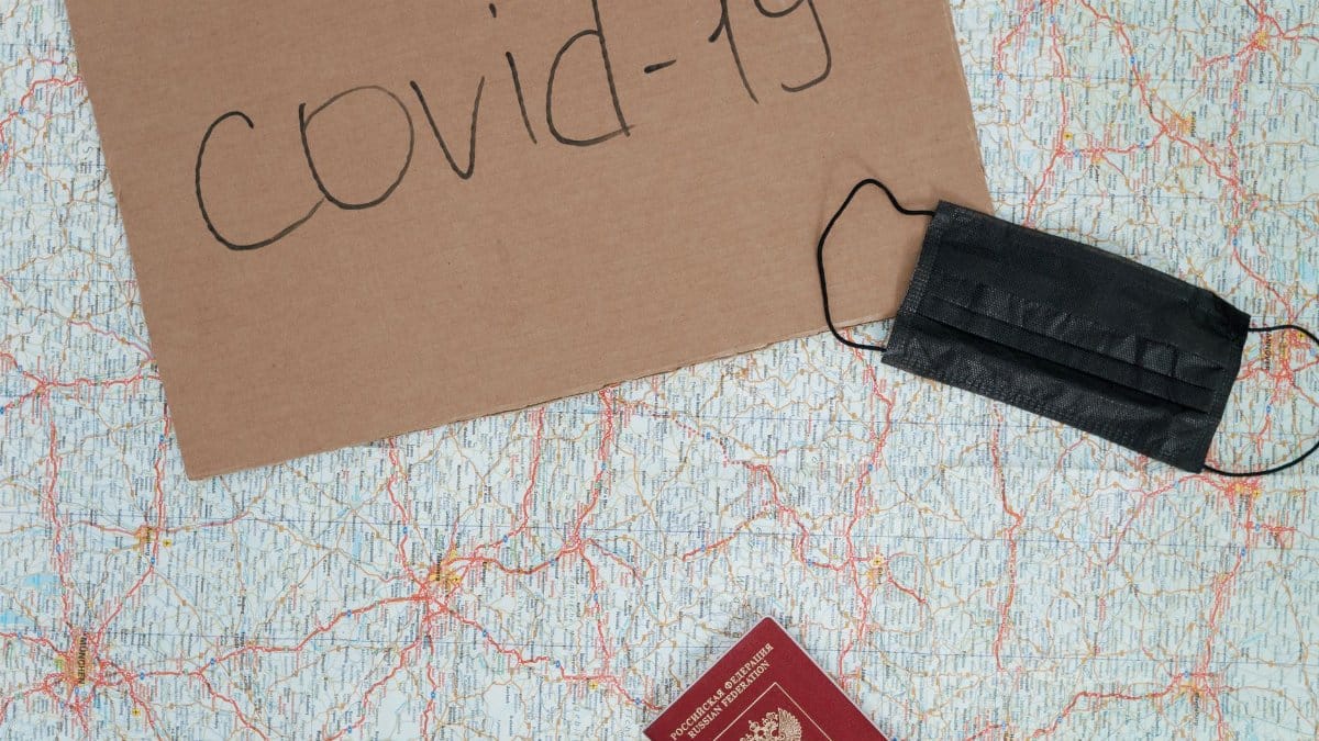 A placard reading 'covid-19', a map, face mask, and passport representing travel restrictions.
