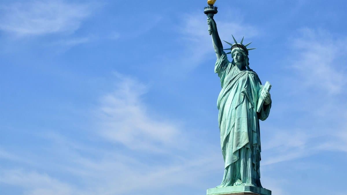 The Statue of Liberty stands tall on Liberty Island under a clear blue sky, symbolizing freedom.