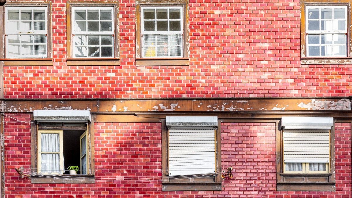 A classic red brick building facade with vintage wooden windows, capturing urban architecture in Porto, Portugal.