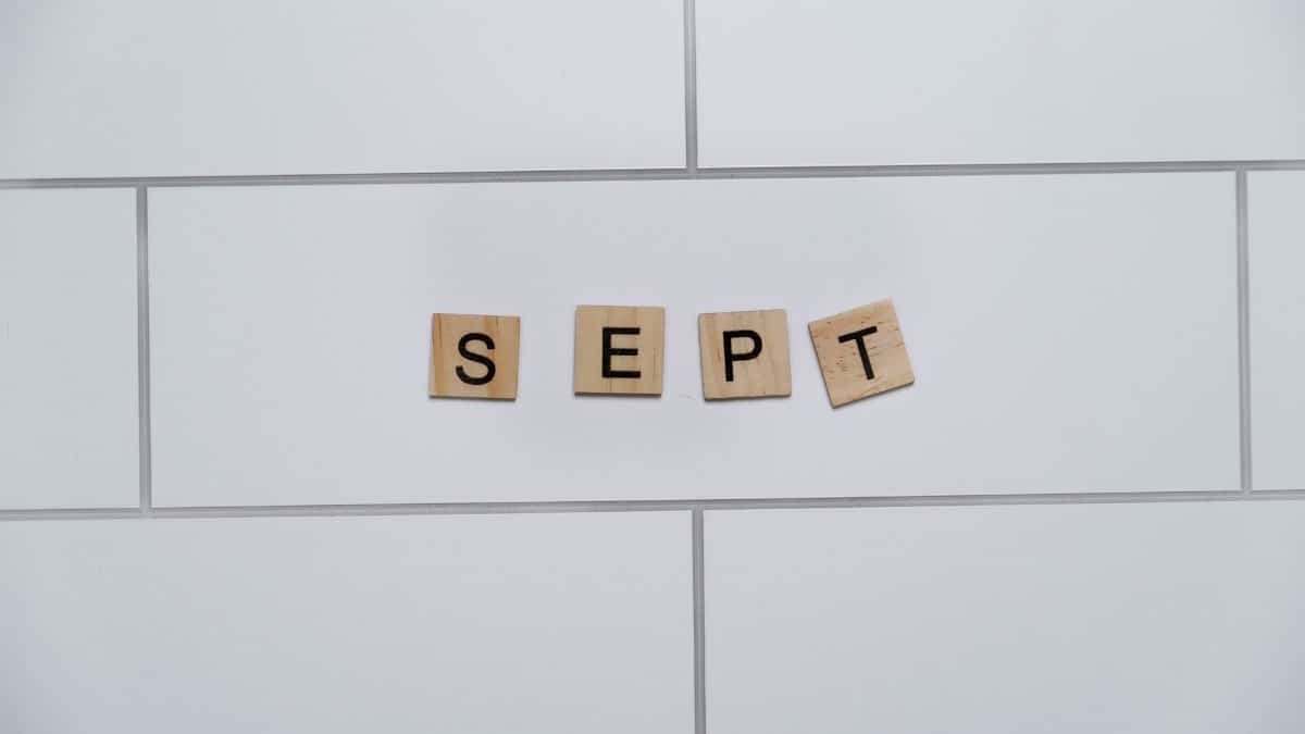 Wooden letter tiles spelling 'Sept' on a white tiled background, perfect for marking calendar events.