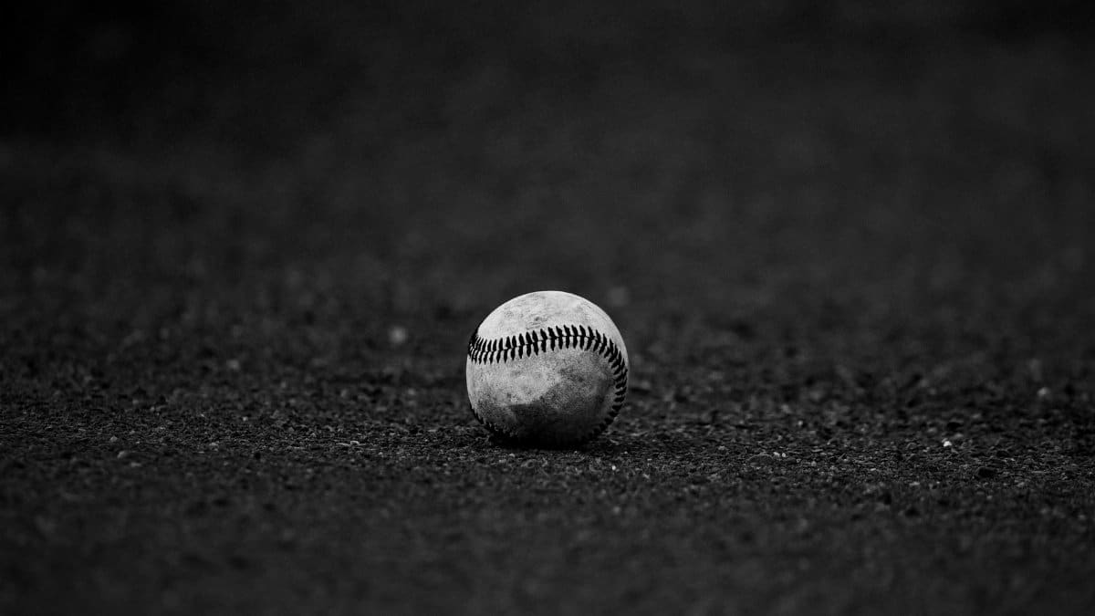 A monochrome image of a baseball resting on a textured dark surface, perfect for sports themes.