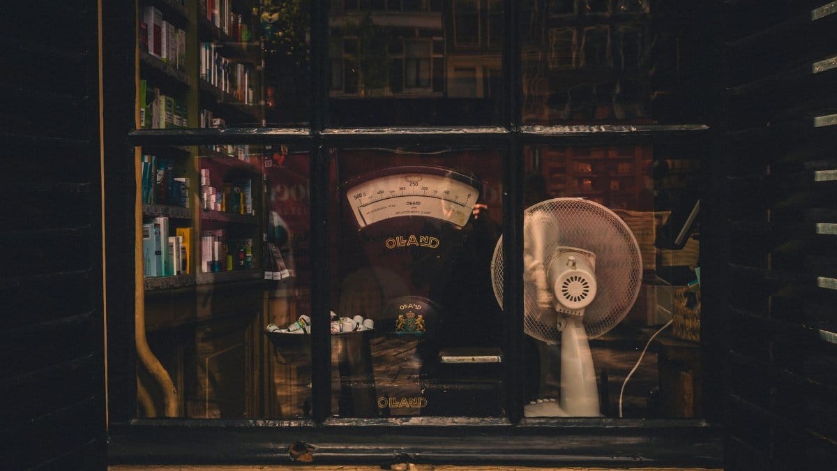 Charming vintage shop window in Amsterdam showcasing old-fashioned scales and fan.
