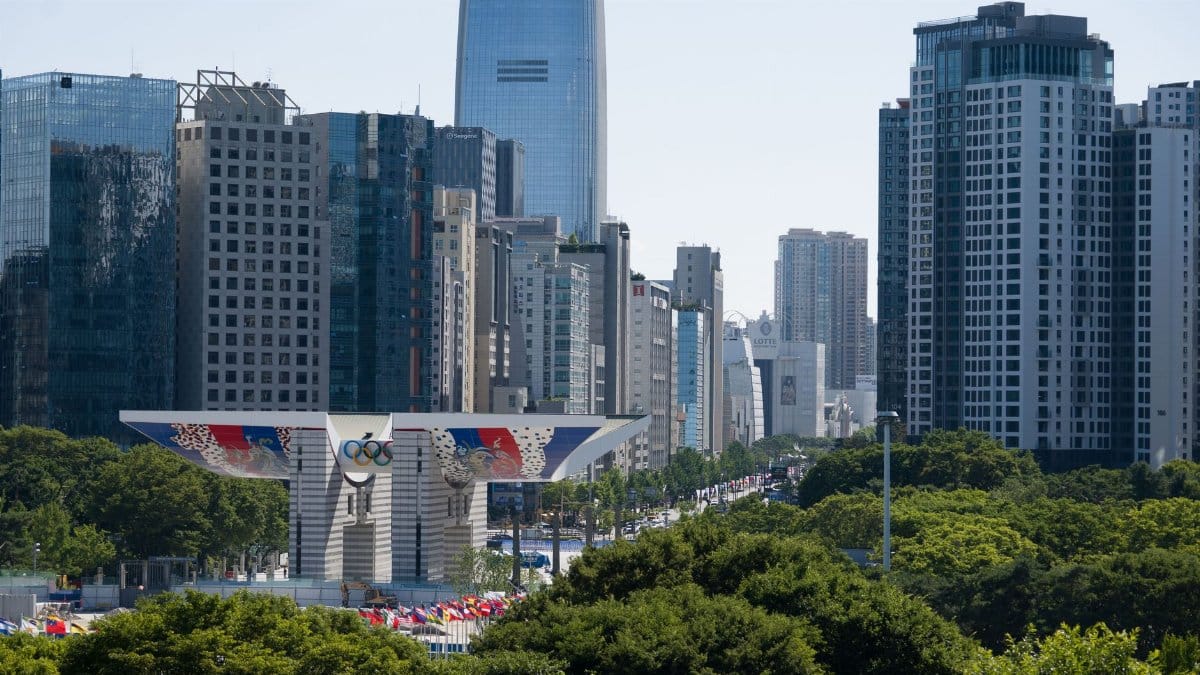 A view of Seoul's modern skyline, featuring the iconic Olympic Gateway, under a clear blue sky.