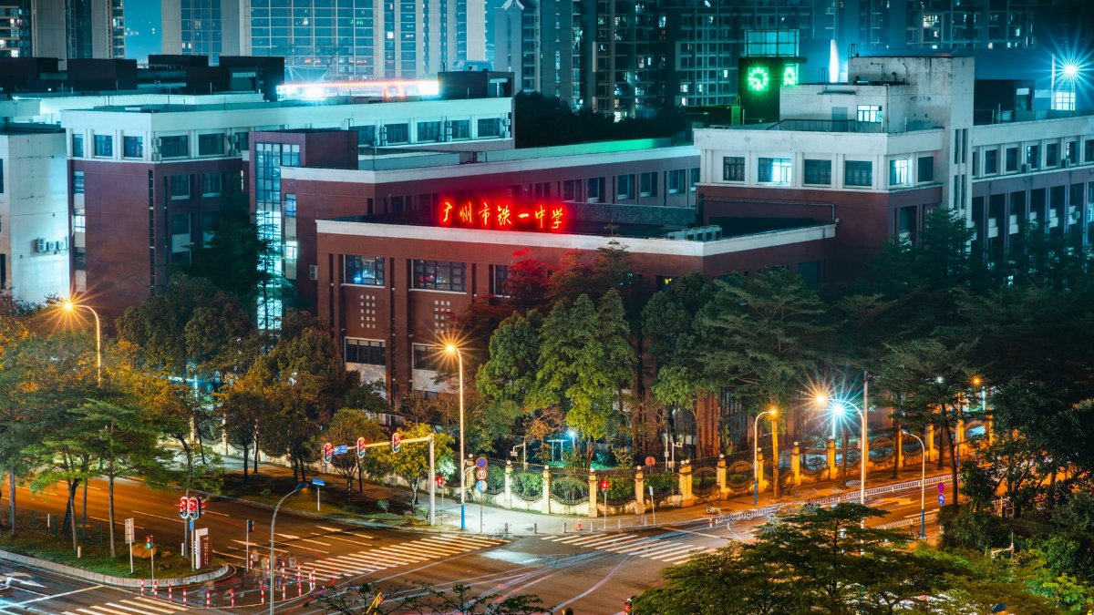 A brightly lit city school building in an urban setting at night with vibrant lights.