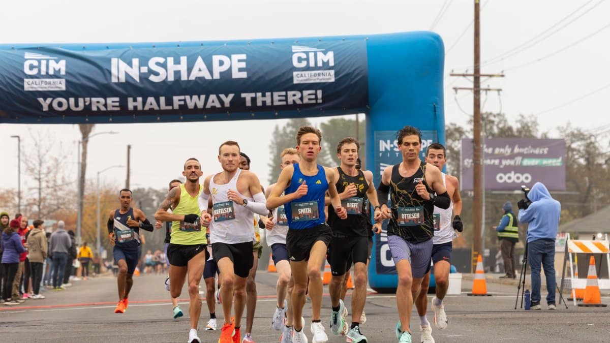 Group of marathon runners passing under a banner during a race event.