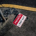 A chained 'Private Keep Out' sign lies on an urban sidewalk, emphasizing security.