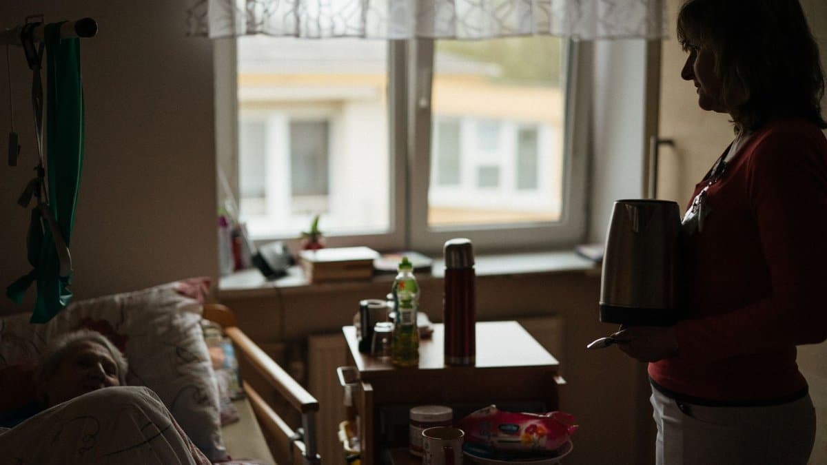 A caregiver prepares a warm drink for a senior in a peaceful retirement home setting.
