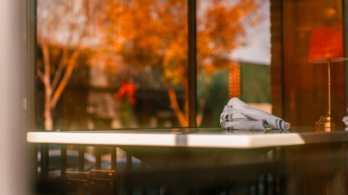 Warm ambiance at a restaurant table with a view of autumn leaves and soft lighting.