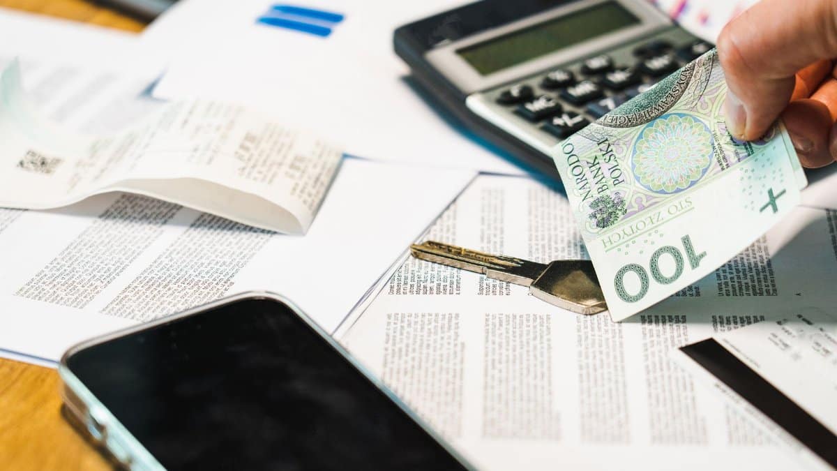 Close-up of financial documents, calculator, and Polish Zloty currency on a desk.