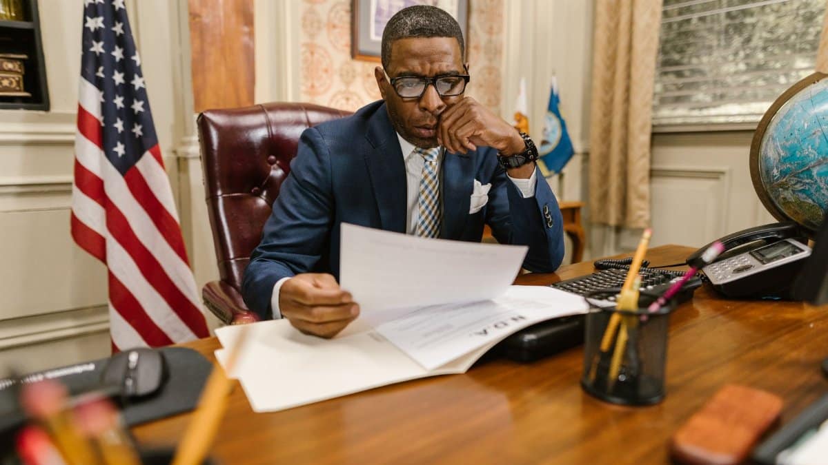 A lawyer in a suit deeply engaged in reviewing legal documents at his office desk.