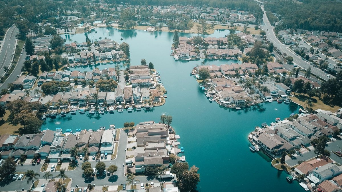 Scenic aerial view of a residential area with houses and water channels, surrounded by roads and greenery.
