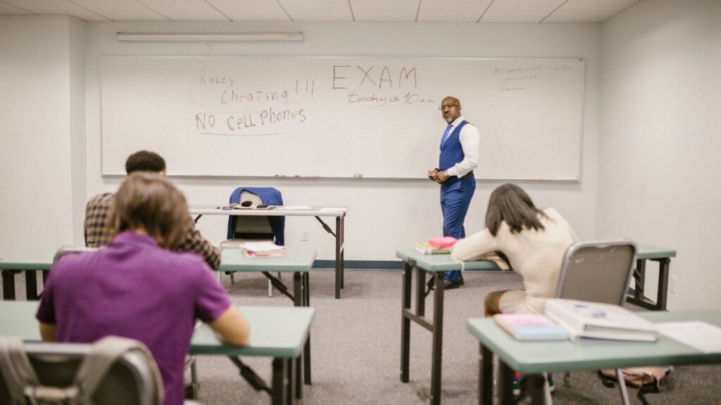 A college educator proctoring an exam, enforcing no cheating rules.