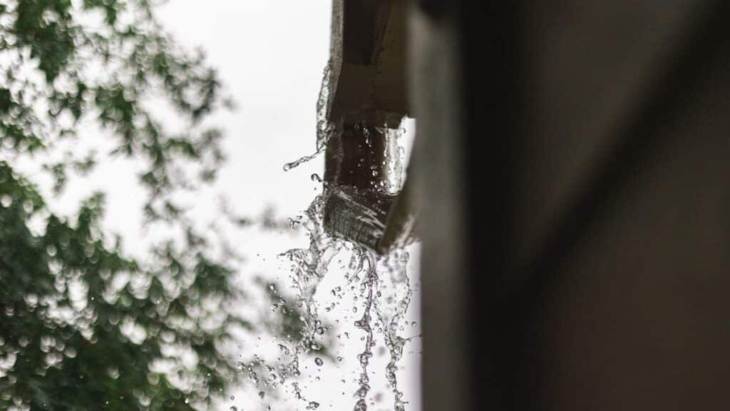 Close-up of rainwater pouring from a gutter, captured during a rainfall in Houston.