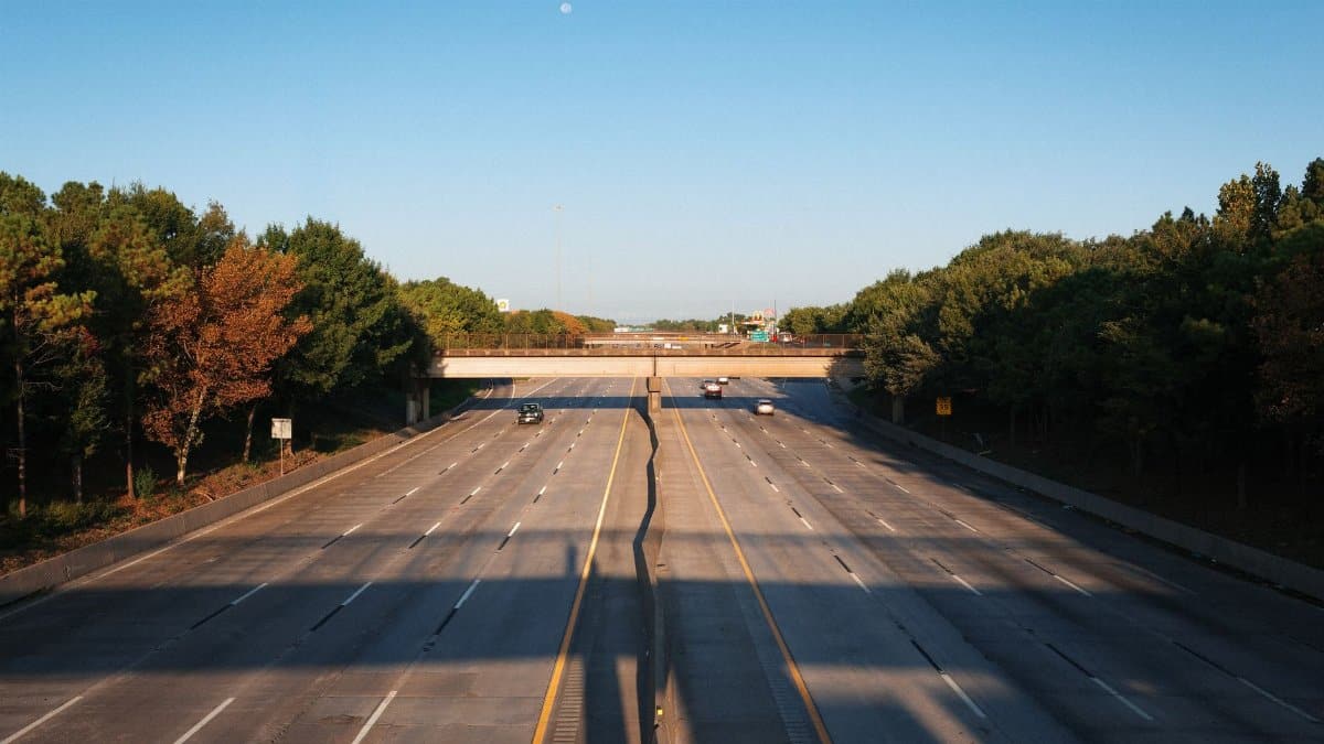 An empty highway in Houston, Texas, featuring autumn-colored trees and a clear sky.