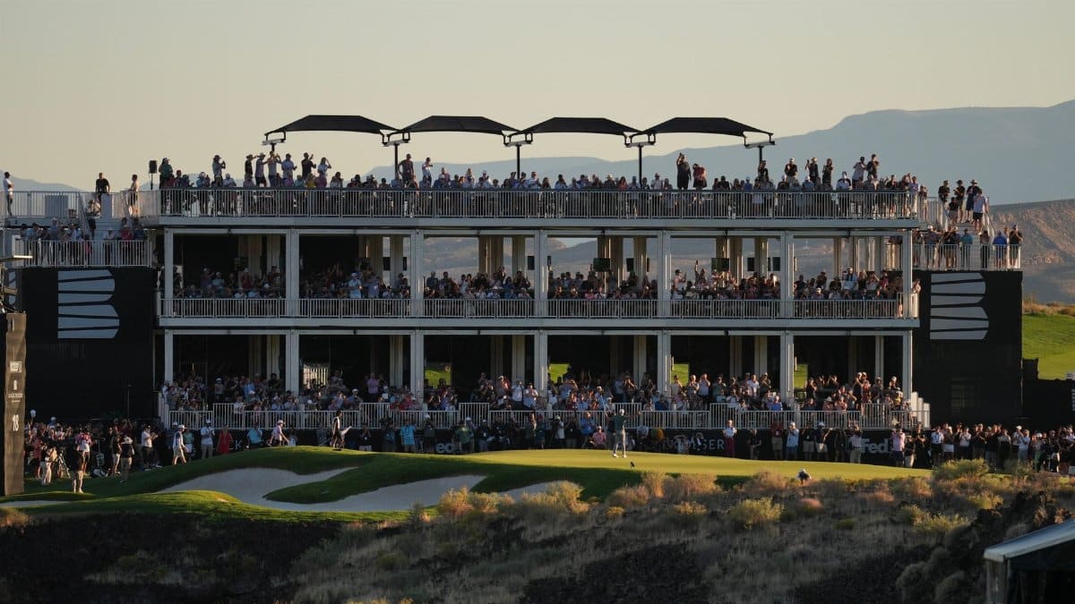 Large crowd gathers on multi-level viewing structure at a golf event during sunset.