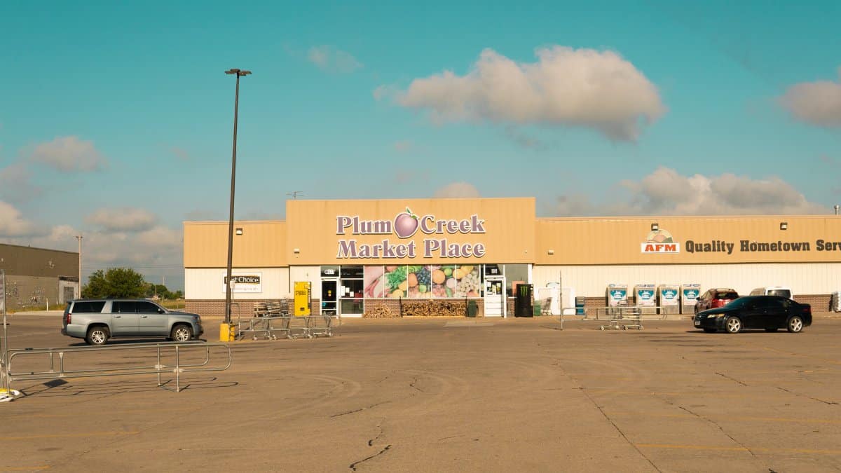 Front view of Plum Creek Market Place with empty parking lot under a clear sky.