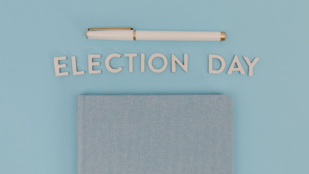 Blue notebook and pen against a light blue background reading 'Election Day', ideal for campaign themes.