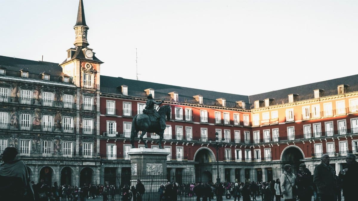 A lively scene at Plaza Mayor, Madrid, featuring historic architecture and a statue.