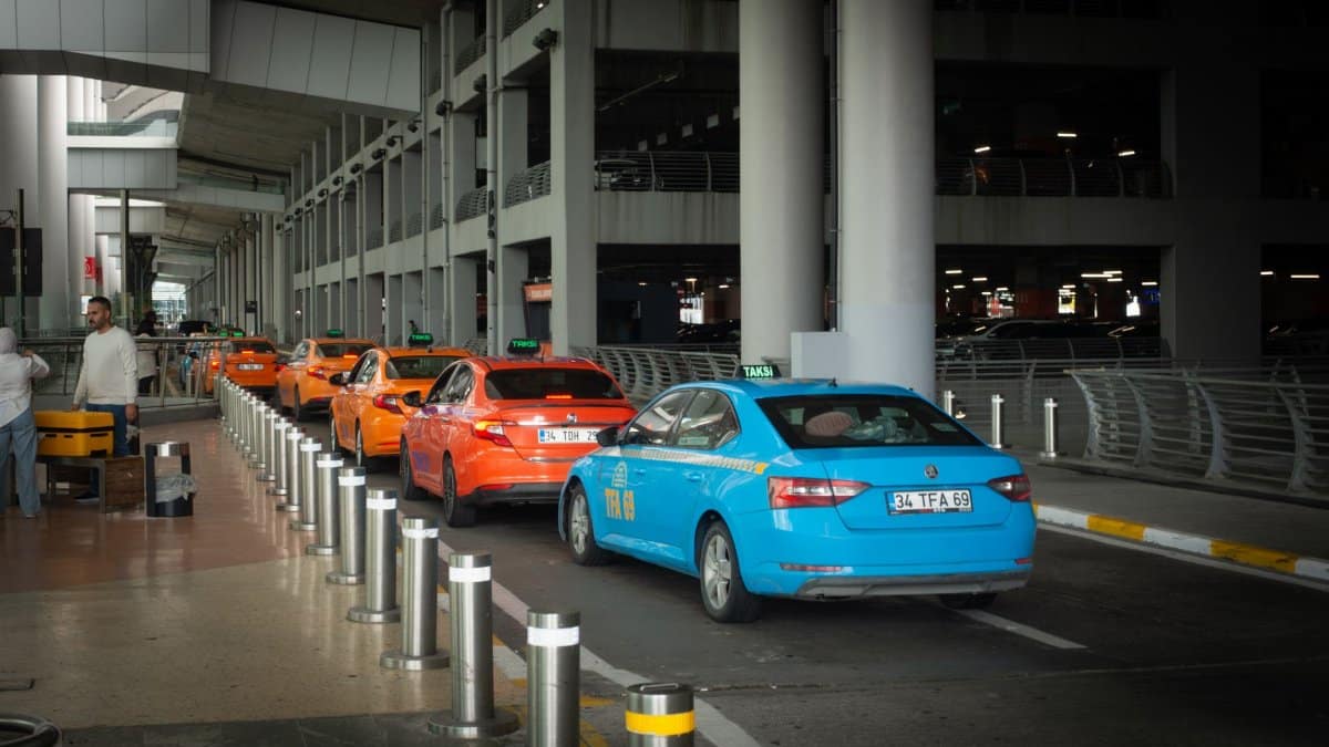 Vibrant taxis lined up at Istanbul Airport arrival terminal with passengers and drivers interacting.